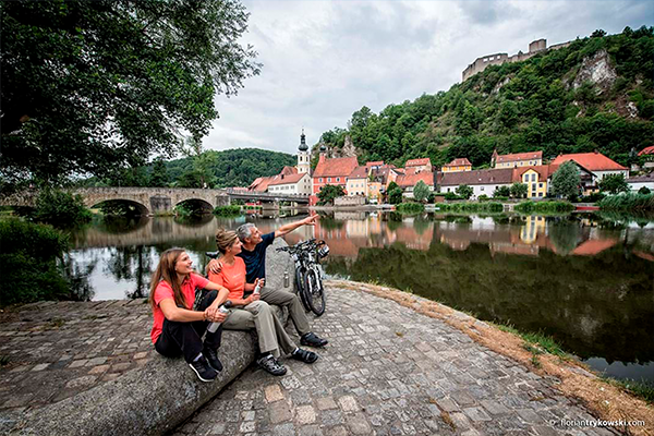 Imagebild Radeln an der Donau: Familie sitzt am Flussufer und genießt die Aussicht